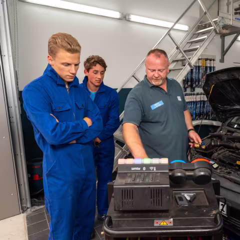 Schüler in einer Werkstatt bei der Reparatur eines Autos